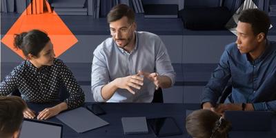 Photo of five staff members talking with ipads and notepads